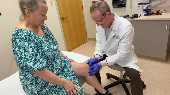 doctor treating a female patient's knee for pain