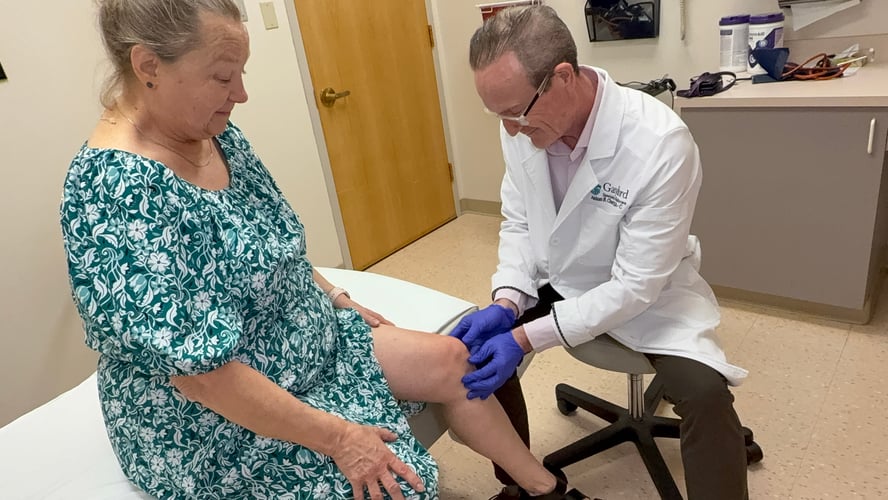 doctor treating a female patient's knee for pain